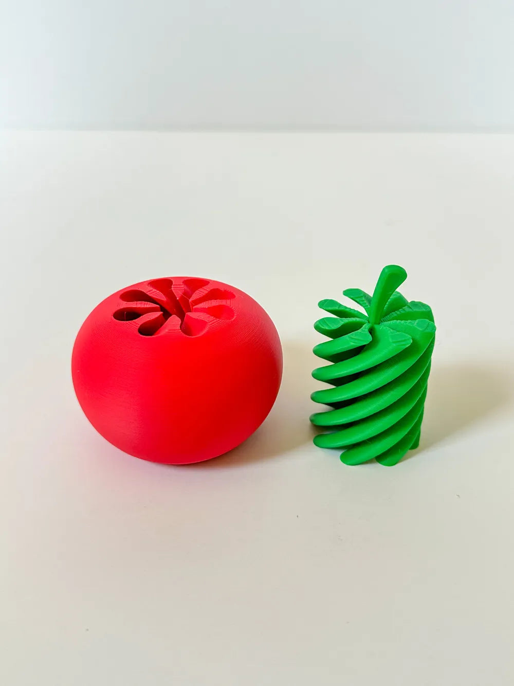 Tomato Twist toy shown open with red tomato base and green twisting insert
